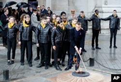 El presidente francés, Emmanuel Macron, acompañado de varios niños enciende la llama en la Tumba del Soldado Desconocido bajo el Arco de Triunfo durante las ceremonias por los 100 años del fin de la Primera Guerra Mundial, el 11 de noviembre de 2018 en París.
