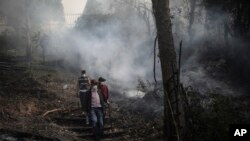 Residentes caminan en un área carbonizada por un incendio forestal en Nemocón, al norte de Bogotá, Colombia, el martes 23 de enero de 2024.