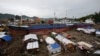 FILE - Typhoon survivors living in temporary shelters are seen near ships that ran aground, nearly 100 days after super Typhoon Haiyan devastated Tacloban city in central Philippines.