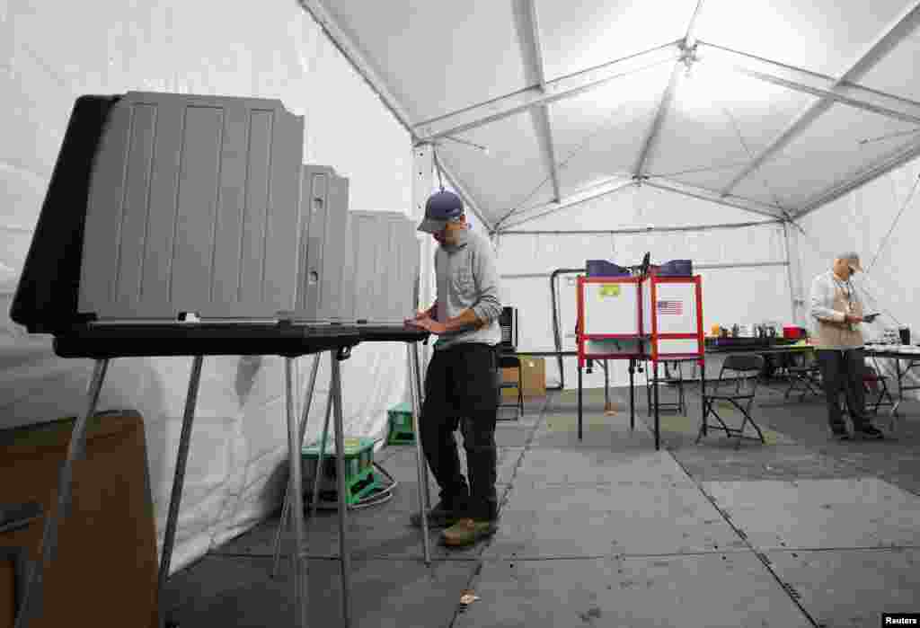 Un hombre vota en un sitio de votación temporal ubicado en una tienda de campaña debido a los daños causados por el huracán Helene, en Black Mountain, Carolina del Norte.