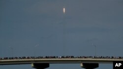 Los espectadores observan desde un puente en Titusville, Florida, mientras el SpaceX Falcon 9 despega con dos astronautas a bordo el 30 de mayo de 2020.
