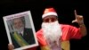 ARCHIVO - Un partidario del presidente brasileño Luiz Inácio Lula da Silva vestido de Papá Noel señala la letra "L" de Lula, con una foto que dice en portugués "¡Salud Presidente!", durante una reunión de apoyo al líder en Brasilia, Brasil, el 10 de diciembre de 2024.