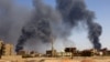 FILE - A man walks while smoke rises above buildings after aerial bombardment, during clashes between the paramilitary Rapid Support Forces and the army in Khartoum North, Sudan, May 1, 2023. 