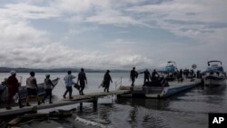 Migrantes abordan un barco hacia el Tapón del Darién, en Necoclí, Colombia, el 7 de octubre de 2023.