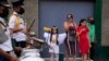 Residentes miran a la banda de música de la escuela durante un desfile de madres e hijos en un comedor de beneficencia celebrando la Navidad en el barrio Antimano de Caracas, Venezuela, el jueves 16 de diciembre de 2021.