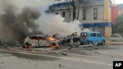 En esta fotografía tomada de un video publicado por el canal de telegramas del Ministerio de Situaciones de Emergencia de Rusia el sábado 30 de diciembre de 2023, los bomberos apagan autos en llamas después de un bombardeo en Belgorod, Rusia.