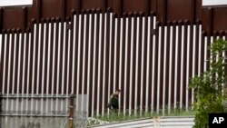 ARCHIVO - Un agente de la Patrulla Fronteriza de EEUU camina junto a una valla que separa a Tijuana, México, de San Diego, en San Diego, el 18 de marzo de 2020