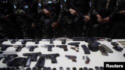 Elementos de la Policía Militar de Orden Público hacen guardia, al presentar armas y cargadores incautados en el penal de Támara, luego de que las Fuerzas Armadas de Honduras tomaran el control de los penales a nivel nacional como parte del operativo "Fe y Esperanza", en las afueras de Tegucigalpa, Honduras 26 de junio de 2023.