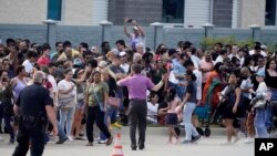 ARCHIVO - Personas se reúnen frente a un centro comercial después de un tiroteo masivo donde murieron 8 personas, el 6 de mayo de 2023 en Allen, EEUU.