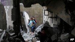 Niños palestinos caminan después de un ataque israelí contra edificios residenciales en Rafah, Franja de Gaza, el jueves 14 de diciembre de 2023.