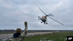 Un soldado ucraniano saluda a un helicóptero militar que regresa del combate, cerca del frente en la región de Kherson, Ucrania, el domingo 8 de enero de 2023. (Foto AP/LIBKOS)