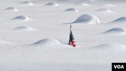 En el cementerio de veteranos de guerra en East Hartford, Connecticut, las tumbas aparecen cubiertas de nieve y una bandera apenas puede verse.