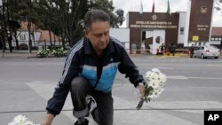 Un hombre coloca flores en un memorial improvisado frente a la Academia de Policía General Francisco de Paula Santander, un día después de que explotara un coche bomba en el lugar.