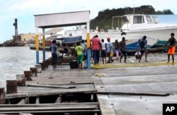 Personas en St. John, Antigua y Barbuda recuperan partes de un muelle que se rompió tras el paso del huracán Irma. Sept. 6, 2017.