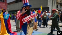 ARCHIVO - Un hombre vestido como el personaje estadounidense Tío Sam sostiene un cartel de la petrolera Exxon durante una marcha por el Esequibo, en Caracas, Venezuela, el 26 de septiembre de 2023. 