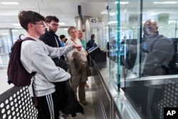 Piet De Staercke, his wife Jill Bornauw, and their eldest son Stan De Staercke watch their youngest Tuur de Staercke, get screened by a Customs Border Protection officer at Washington Dulles International Airport in Virginia, April 1, 2024. (AP Photo/Manuel Balce Ceneta)