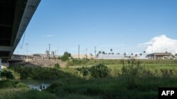 Migrantes lavan ropa y se bañan en las orillas mexicanas del Río Grande. Por encima está el Puente Internacional en Matamoros, estado de Tamaulipas, México, el 5 de noviembre de 2019.
