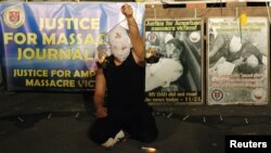 A masked Filipino artist holds up a replica of a burning weighing scale signifying justice to commemorate the 2nd year anniversary of the "Maguindanao Massacre" at the National Press Club compound in Manila, November 23, 2011.