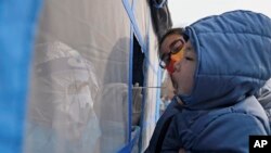 Un trabajador sanitario recopila una muestra de un niño durante una prueba diagnóstica en, en el municipio de Tianjin, en el norte de China, el 9 de enero de 2022.