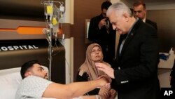 El primer ministro de Turquía, Binali Yildirim, habla con un hombre hospitalizado en Estambul, herido durante el ataque a una discoteca.