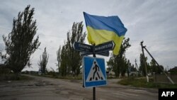 Una fotografía tomada el 27 de septiembre de 2022 muestra una bandera ucraniana ondeando en una calle del pueblo recientemente liberado de Vysokopillia, región de Kherson, en medio de la invasión rusa de Ucrania.
