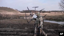 ARCHIVO - En esta foto tomada de un video publicado por el Servicio de Prensa del Ministerio de Defensa de Rusia el lunes 25 de marzo de 2024, un soldado ruso lleva un dron ucraniano capturado.