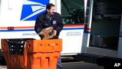 ARCHIVO - Un empleado del Servicio Postal de EE. UU. carga paquetes afuera de una oficina postal en Wheeling, Illinois, el 29 de enero de 2024.