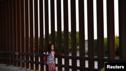 Una pequeña, que forma parte de un grupo de migrantes llegados de Centroamérica, camina junto a la valla fronteriza que separa EE. UU. y México, tras entrar al país de manera irregular, el 6 de abril de 2019.