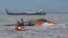 Rescuers tie a rope at the capsized vessel MBCA Kim-Nirvana to pull it towards the shore near a port in Ormoc city, central Philippines, July 3, 2015. 