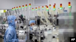 资料照片：2020年5月14日，佩戴保护设备的员工在北京记者的政府组织游览期间在瑞萨电子的半导体生产设施中工作。 中国已宣布退税，以便在美国制裁后促进其半导体产业的增长，这些制裁削减了对科技巨头华为和其他一些公司的美国处理器筹码。