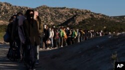 Migrantes chinos esperan ser procesados tras cruzar la frontera con México, el miércoles 8 de mayo de 2024, cerca de Jacumba Hot Springs, California.