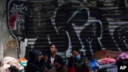 ARCHIVO - Migrantes venezolanos esperan ayuda frente a la Comisión Mexicana de Ayuda a Refugiados en la Ciudad de México, en octubre de 2019.