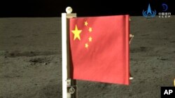 En esta imagen proporcionada por la Administración Espacial Nacional China (CNSA), publicada por la agencia de noticias Xinhua, muestra una bandera nacional china transportada por el módulo de aterrizaje en la cara oculta de la Luna, el martes 4 de junio de 2024. 