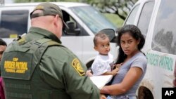 Una madre que migra desde Honduras sostiene a su hijo de 1 año mientras se entrega a agentes de la Patrulla Fronteriza de EE.UU. después de cruzar ilegalmente la frontera el lunes 25 de junio de 2018, cerca de McAllen, Texas. (AP Photo / David J. Phillip)