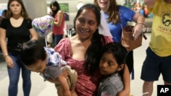 Archivo- Buena Ventura Martin-Godinez, (centro) tiene a su hijo Pedro, a la izquierda, mientras se reúne con su hija Janne, a la derecha, en el Aeropuerto Internacional de Miami, el 1 de julio de 2018.