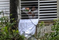 Yunior García, disidente cubano, saluda desde su ventana mientras permanece bloqueado por simpatizantes del gobierno.