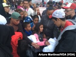Recibiendo instrucciones y cobijas para pasar la noche en la frontera. (A. Martínez/VOA).