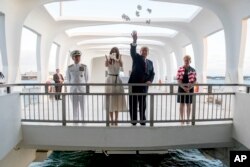 El presidente Trump y la primera dama Melania Trump, acompañados por el comandante de comando Harry Harris, y su esposa, Bruni Bradley, esparcieron pétalos de pikake mientras visitaban el Monumento de Pearl Harbor en Honolulu, Hawai, el 3 de noviembre de 2017.