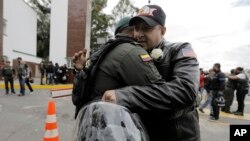 Un hombre abraza a un oficial de policía, afuera de la Academia de Policía General Francisco de Paula Santander, un día después de que explotara un coche bomba en el lugar, en Bogotá.