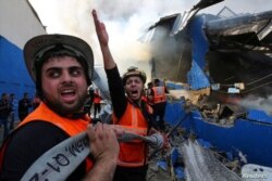 Un bombero palestino reacciona mientras trabaja para apagar un incendio en una fábrica de esponjas después de que fue alcanzada por proyectiles de artillería israelí, según testigos, en el norte de la Franja de Gaza, el 17 de mayo de 2021.
