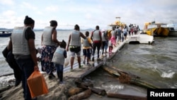 Migrantes, en su mayoría haitianos, abordan un bote en Necoclí, Colombia, con destino a Acandí, para luego cruzar a Panamá y continuar hacia el norte, el 23 de septiembre de 2021. Archivo.