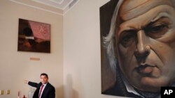 Carlos Vecchio, político exiliado que Estados Unidos reconoce como embajador de Venezuela, señala una sección vacía de una pared donde una vez colgaba una obra de arte en la residencia del embajador en Washington.