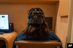 Emily Hollenbeck, a deep brain stimulation therapy patient, demonstrates an EEG device that records brain activity as she reacts to short videos at Mount Sinai’s “Q-Lab” in New York on Dec. 20, 2023. (AP Photo/Mary Conlon)