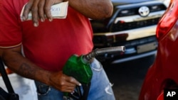 Un trabajador pone gasolina a un vehículo en una estación de servicio PDVSA en Caracas, Venezuela.