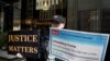 Una mujer sostiene pancartas frente a la Trump Tower neoyorquina, días después de que el expresidente de EEUU, Donald Trump, afirmara que esperaba ser arrestado y pedía a sus seguidores que protestaran en Nueva York, el 22 de marzo de 2023