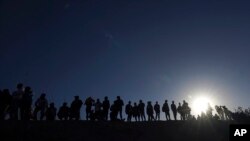 ARCHIVO - Migrantes se encuentran en el lado mexicano de la frontera entre Estados Unidos y México, a orillas del Río Grande, en Ciudad Juárez, México, el 29 de marzo de 2023.