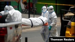 ARCHIVO - Empleados funerarios retiran a una víctima de COVID-19 de un hospital en El Salvador.