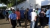 Una mujer policía pasa junto a personas que hacen cola para ingresar a una escuela utilizada como mesa de votación, durante las elecciones presidenciales, en Managua, Nicaragua, el 7 de noviembre de 2021. REUTERS 