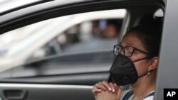 Una mujer que usa una máscara para frenar la propagación del nuevo coronavirus, asiste a una misa en autocine en Chia, Colombia, el domingo 30 de agosto de 2020. 