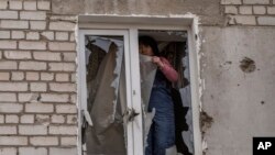 ARCHIVO - Una mujer coloca plástico sobre su ventana dañada después de un ataque ruso la noche anterior, en la zona residencial de Mikolaiv, Ucrania, el 29 de marzo de 2022. AP